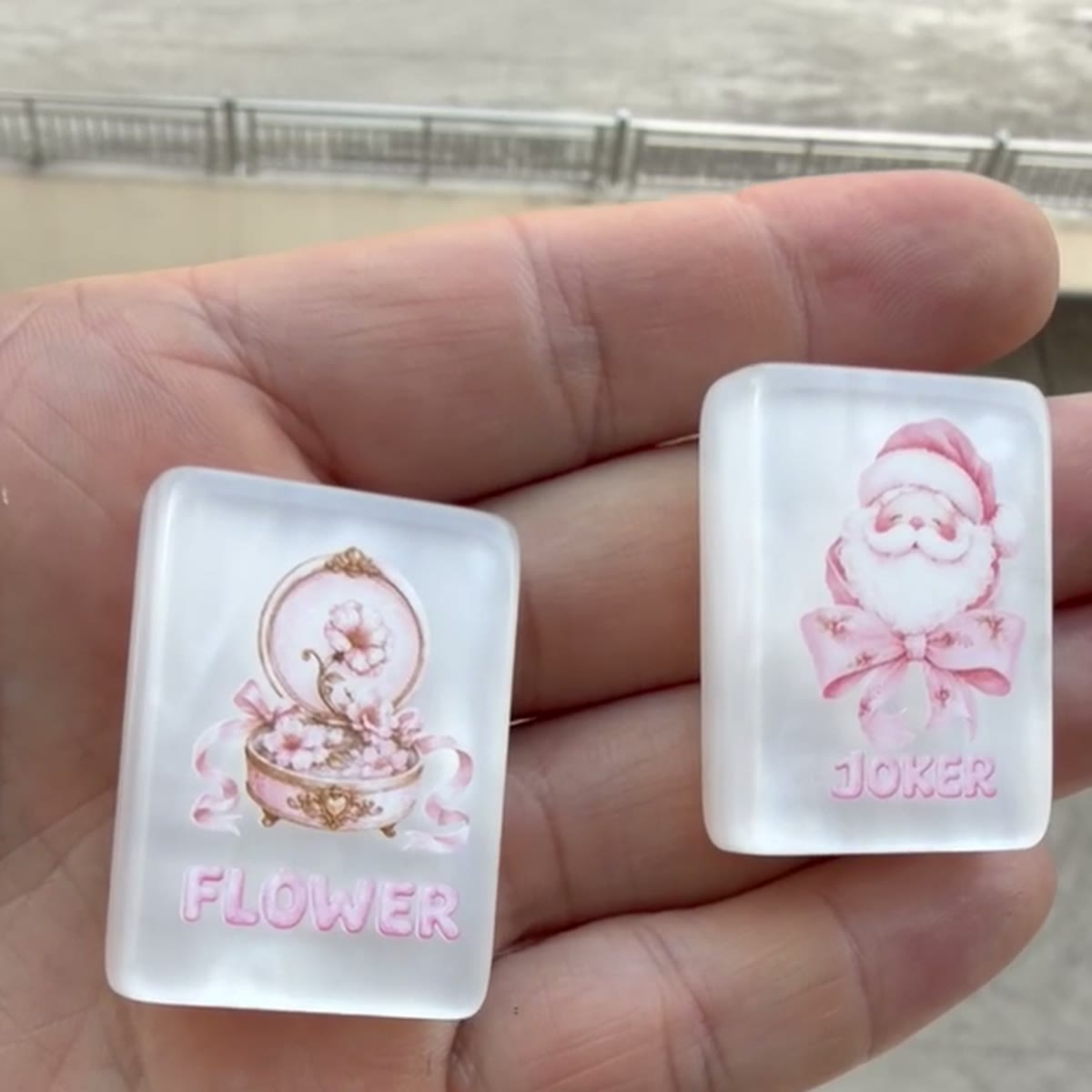 Unfiltered daylight photo holding the Pink Santa Joker and Flower tile from SOLMAY Studio